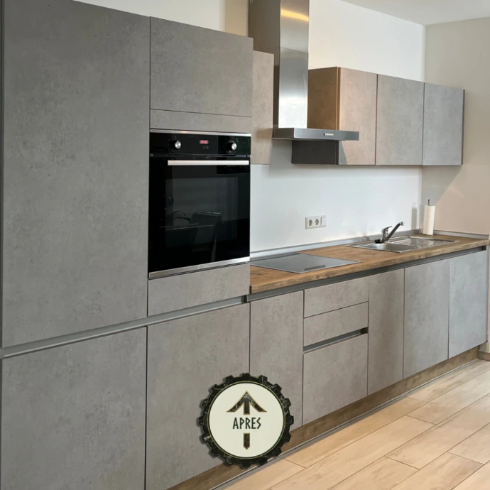 Cuisine modernisée avec façades effet béton et plan de travail bois après rénovation par film architectural. Transformation réalisée par L’Atelier Re-Cover. 